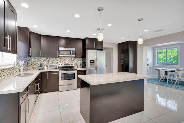 kitchen featuring decorative backsplash, appliances with stainless steel finishes, sink, decorative light fixtures, and a kitchen island