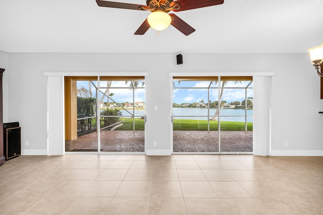 unfurnished living room featuring ceiling fan, a water view, and light tile patterned floors