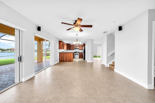 unfurnished living room featuring ceiling fan with notable chandelier, light tile patterned flooring, a water view, and a textured ceiling