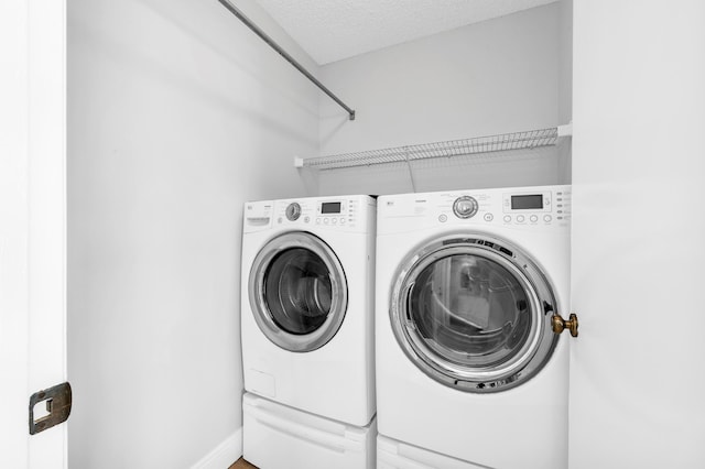 washroom with a textured ceiling and washing machine and clothes dryer