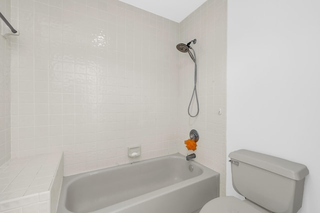 bathroom with tiled shower / bath combo and toilet