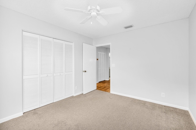 unfurnished bedroom featuring ceiling fan, a closet, carpet floors, and a textured ceiling