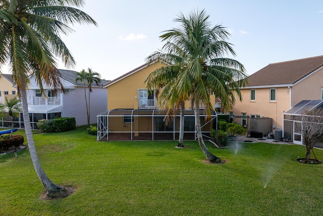 rear view of property featuring a lawn, central AC, and a balcony