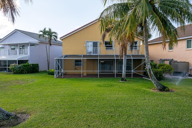 back of house featuring a lawn, glass enclosure, and a balcony