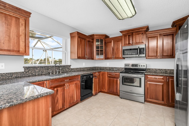 kitchen with light tile patterned flooring, stainless steel appliances, dark stone countertops, and sink