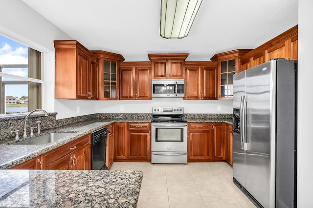 kitchen featuring dark stone countertops, light tile patterned floors, sink, and appliances with stainless steel finishes