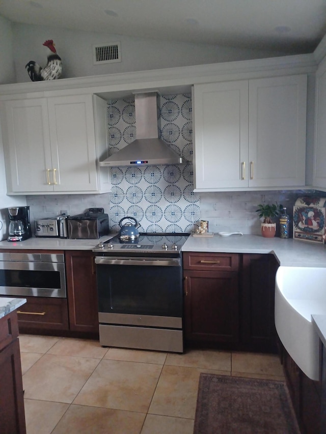 kitchen featuring backsplash, vaulted ceiling, stainless steel range with electric stovetop, and wall chimney exhaust hood