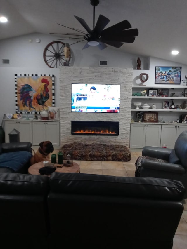 tiled living room with built in shelves, a stone fireplace, and lofted ceiling