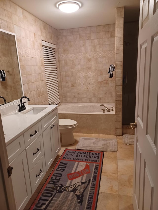 full bathroom with tile patterned floors, toilet, vanity, tile walls, and tiled shower / bath