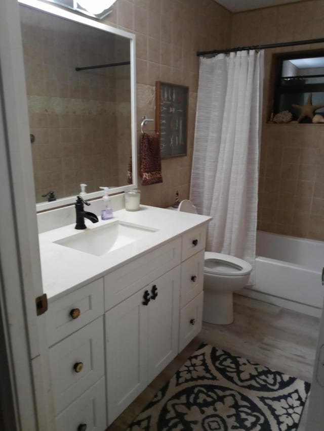 full bathroom with vanity, shower / bathtub combination with curtain, tile walls, hardwood / wood-style floors, and toilet