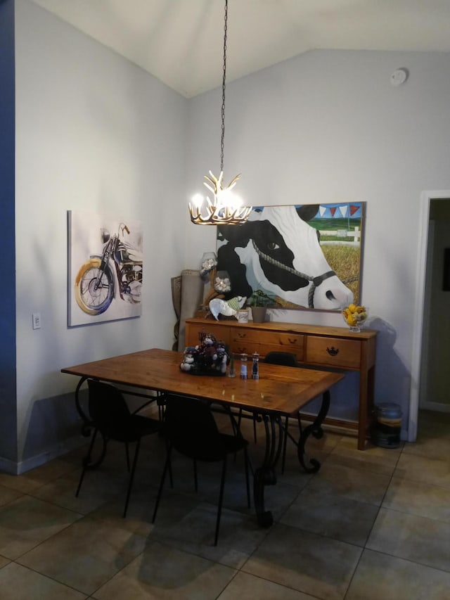 dining area featuring dark tile patterned floors, lofted ceiling, and a notable chandelier