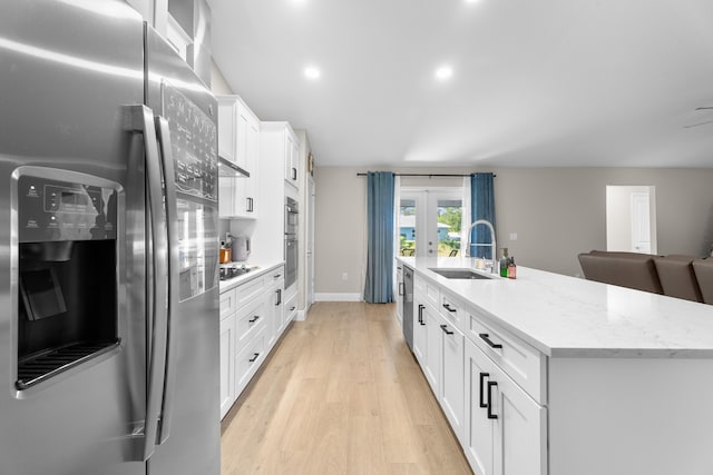 kitchen featuring appliances with stainless steel finishes, french doors, a kitchen island with sink, sink, and white cabinets