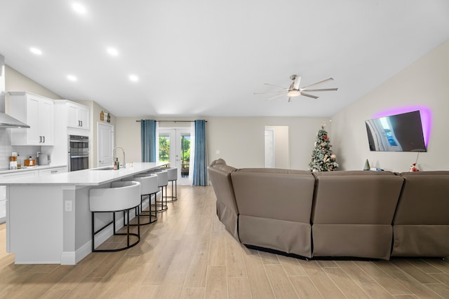 living room featuring ceiling fan, french doors, sink, and light hardwood / wood-style flooring