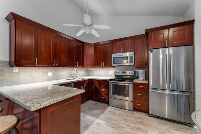 kitchen with ceiling fan, stainless steel appliances, a kitchen breakfast bar, light stone countertops, and sink