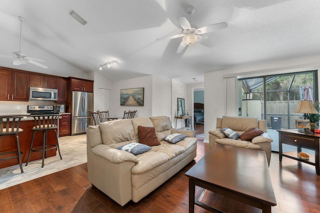 living room with ceiling fan, a textured ceiling, dark hardwood / wood-style flooring, and vaulted ceiling