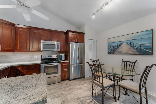 kitchen featuring ceiling fan, backsplash, vaulted ceiling, appliances with stainless steel finishes, and light stone counters