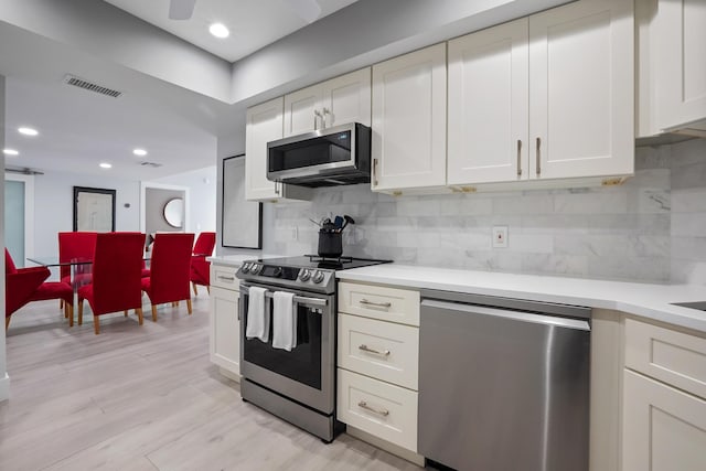 kitchen featuring decorative backsplash, light wood-type flooring, stainless steel appliances, and white cabinetry