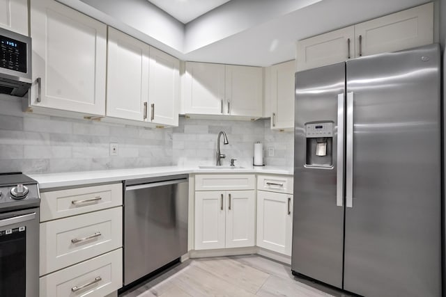 kitchen featuring white cabinets, backsplash, stainless steel appliances, and sink