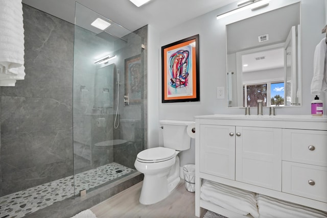 bathroom with tiled shower, vanity, and toilet