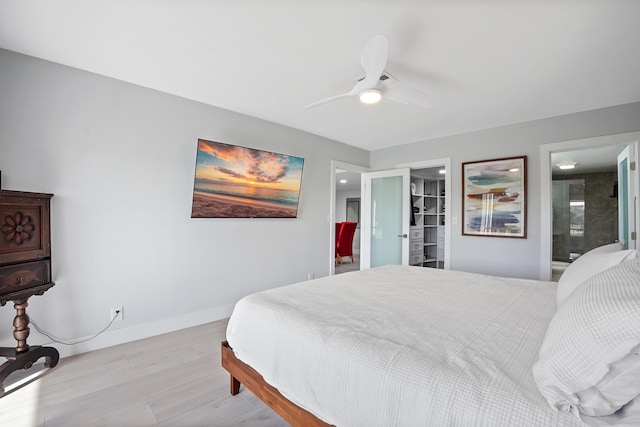 bedroom with a spacious closet, ceiling fan, ensuite bathroom, a closet, and light wood-type flooring