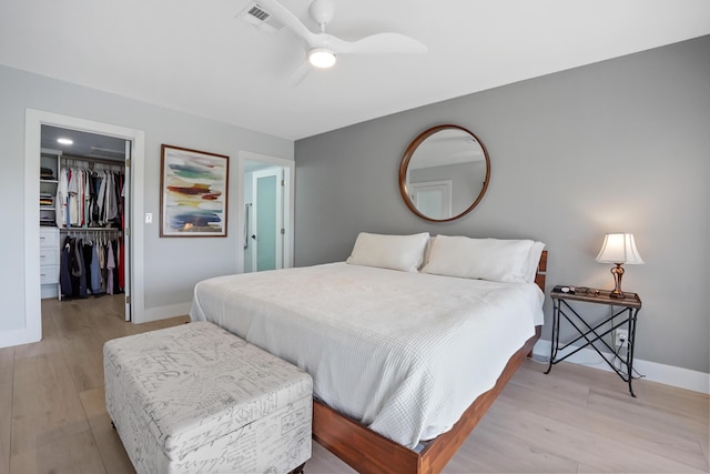 bedroom with a spacious closet, a closet, ceiling fan, and light hardwood / wood-style floors