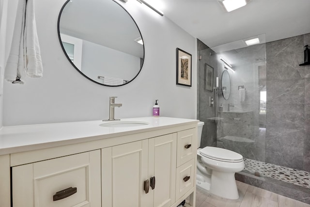 bathroom featuring a tile shower, vanity, and toilet