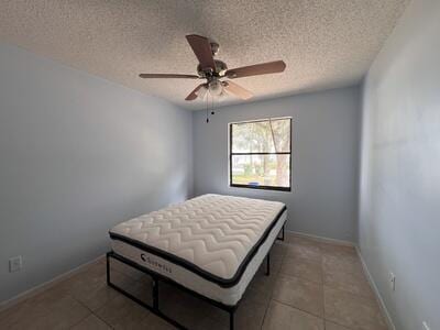 tiled bedroom with ceiling fan and a textured ceiling