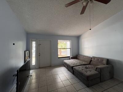 living room featuring light tile patterned floors, a textured ceiling, and ceiling fan