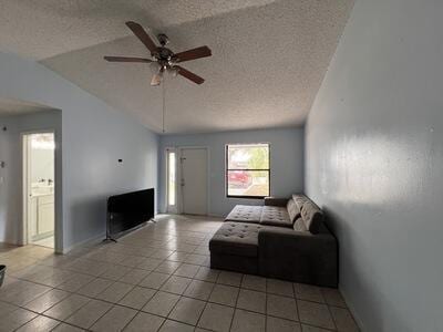 living room with light tile patterned floors, a textured ceiling, ceiling fan, and lofted ceiling