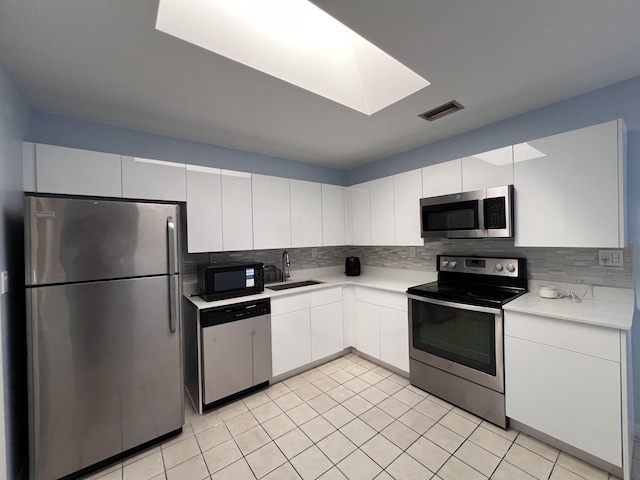 kitchen featuring white cabinets, sink, light tile patterned floors, appliances with stainless steel finishes, and tasteful backsplash