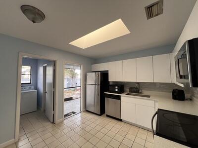 kitchen with a skylight, stainless steel appliances, sink, white cabinets, and washer / clothes dryer