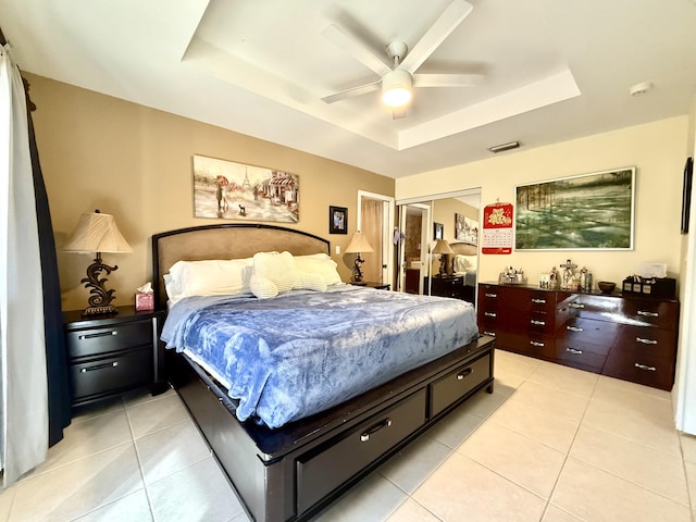 bedroom featuring a raised ceiling, ceiling fan, a closet, and light tile patterned floors