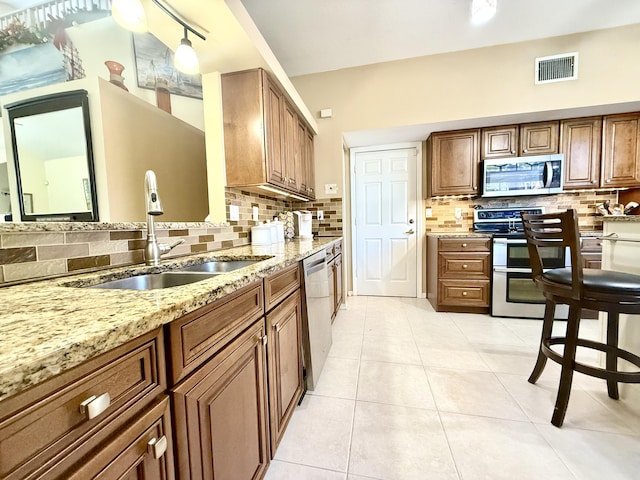 kitchen featuring pendant lighting, sink, decorative backsplash, light tile patterned floors, and stainless steel appliances