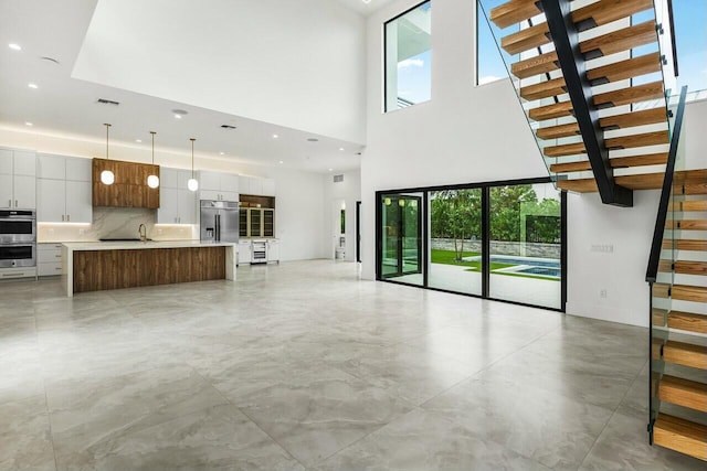 unfurnished living room featuring sink and a high ceiling