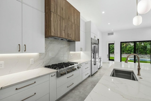 kitchen featuring sink, white cabinets, hanging light fixtures, and stainless steel gas stovetop