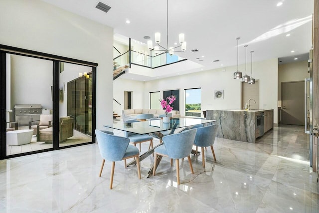 dining space with sink, a high ceiling, and an inviting chandelier