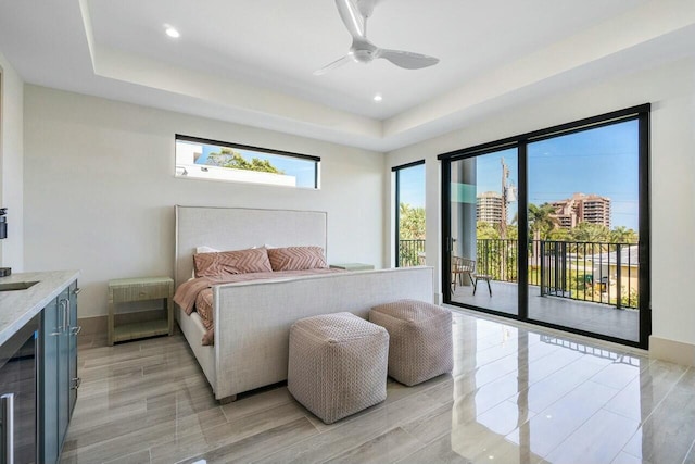 bedroom with access to exterior, a tray ceiling, and ceiling fan