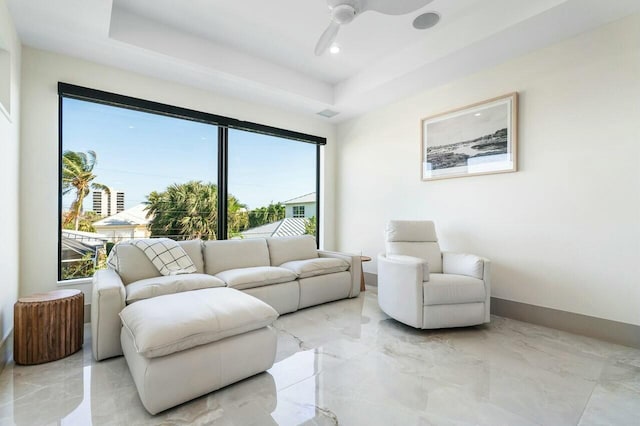 living room featuring a raised ceiling, a wealth of natural light, and ceiling fan