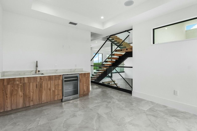 bar with a tray ceiling, wine cooler, and sink