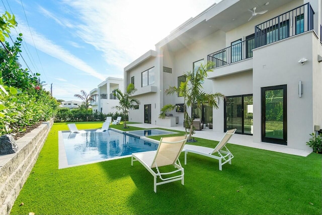 rear view of house with a pool with hot tub, a balcony, a yard, and a patio