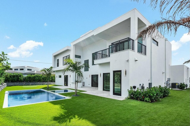 back of property featuring a fenced in pool, central air condition unit, a balcony, and a lawn