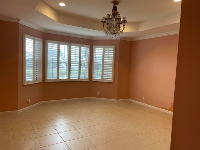 empty room featuring a tray ceiling, light tile patterned floors, a chandelier, and ornamental molding