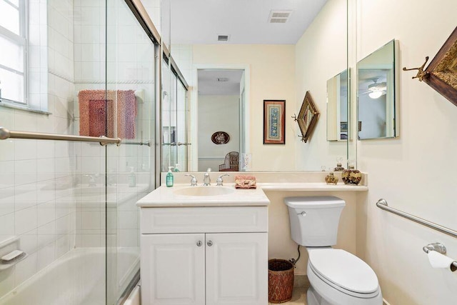 full bathroom featuring vanity, bath / shower combo with glass door, and toilet