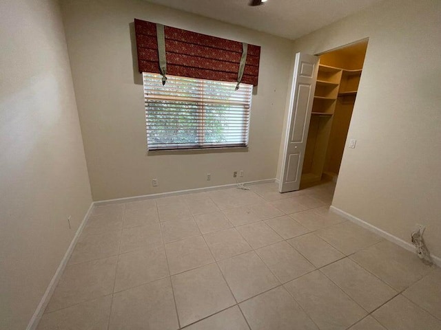 unfurnished bedroom with light tile patterned floors, a walk in closet, and a closet