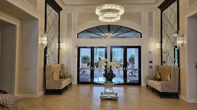 living area featuring a high ceiling, an inviting chandelier, french doors, and wood-type flooring