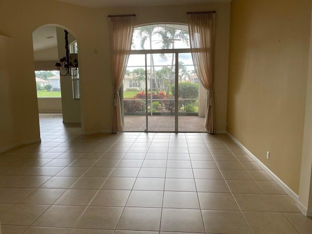 empty room with light tile patterned floors and a chandelier