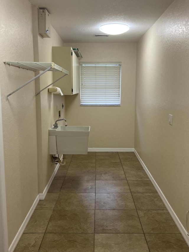 washroom with sink, cabinets, a textured ceiling, and dark tile patterned flooring