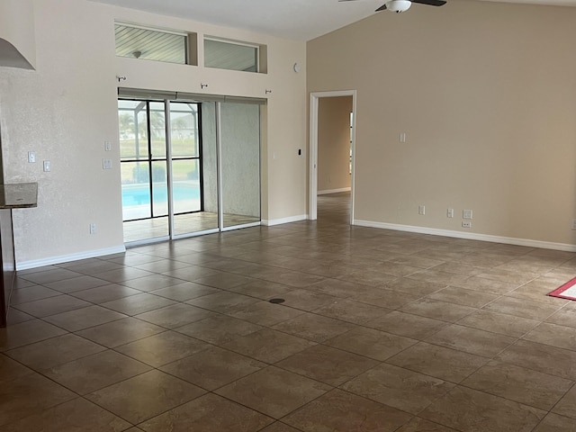 tiled empty room with ceiling fan and high vaulted ceiling