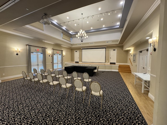 home theater room featuring light hardwood / wood-style floors, ornamental molding, and a tray ceiling