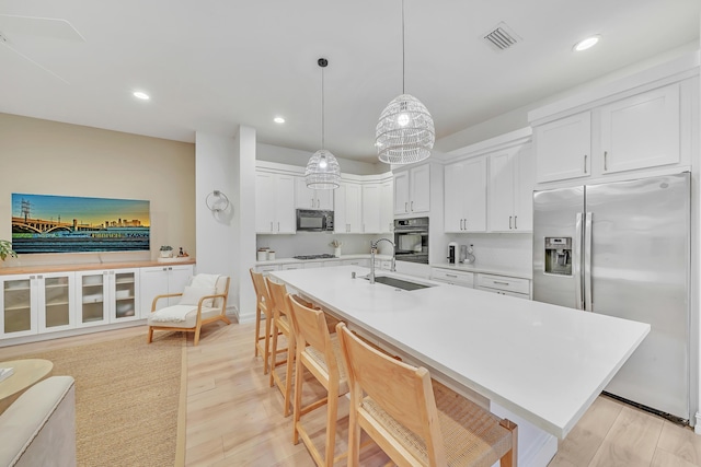 kitchen featuring light wood-type flooring, sink, black appliances, pendant lighting, and white cabinets